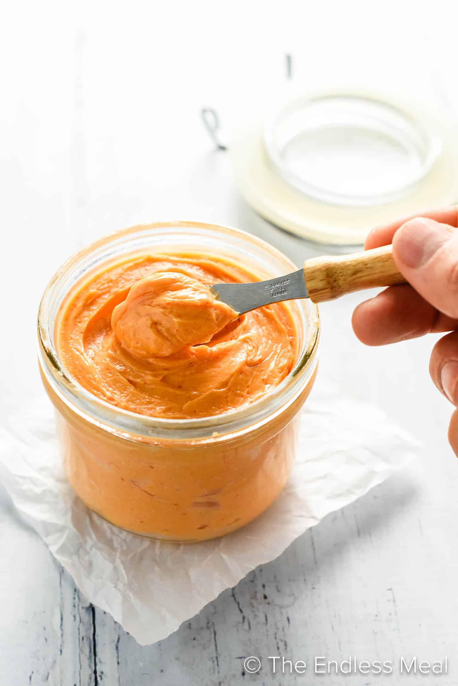 a person scooping Sriracha Butter out of a jar