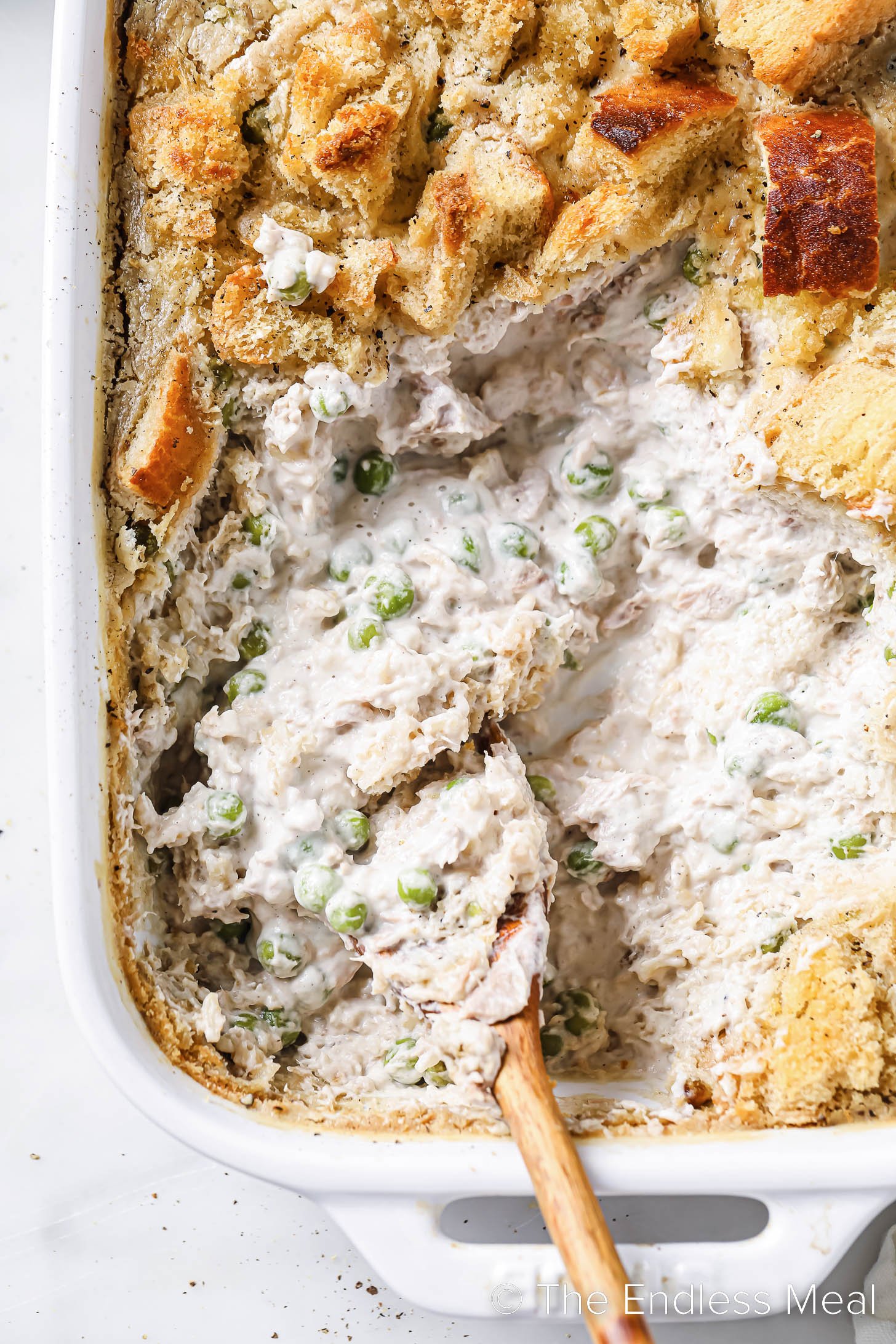 a close up of Healthy Tuna Casserole in a baking dish with a wooden spoon