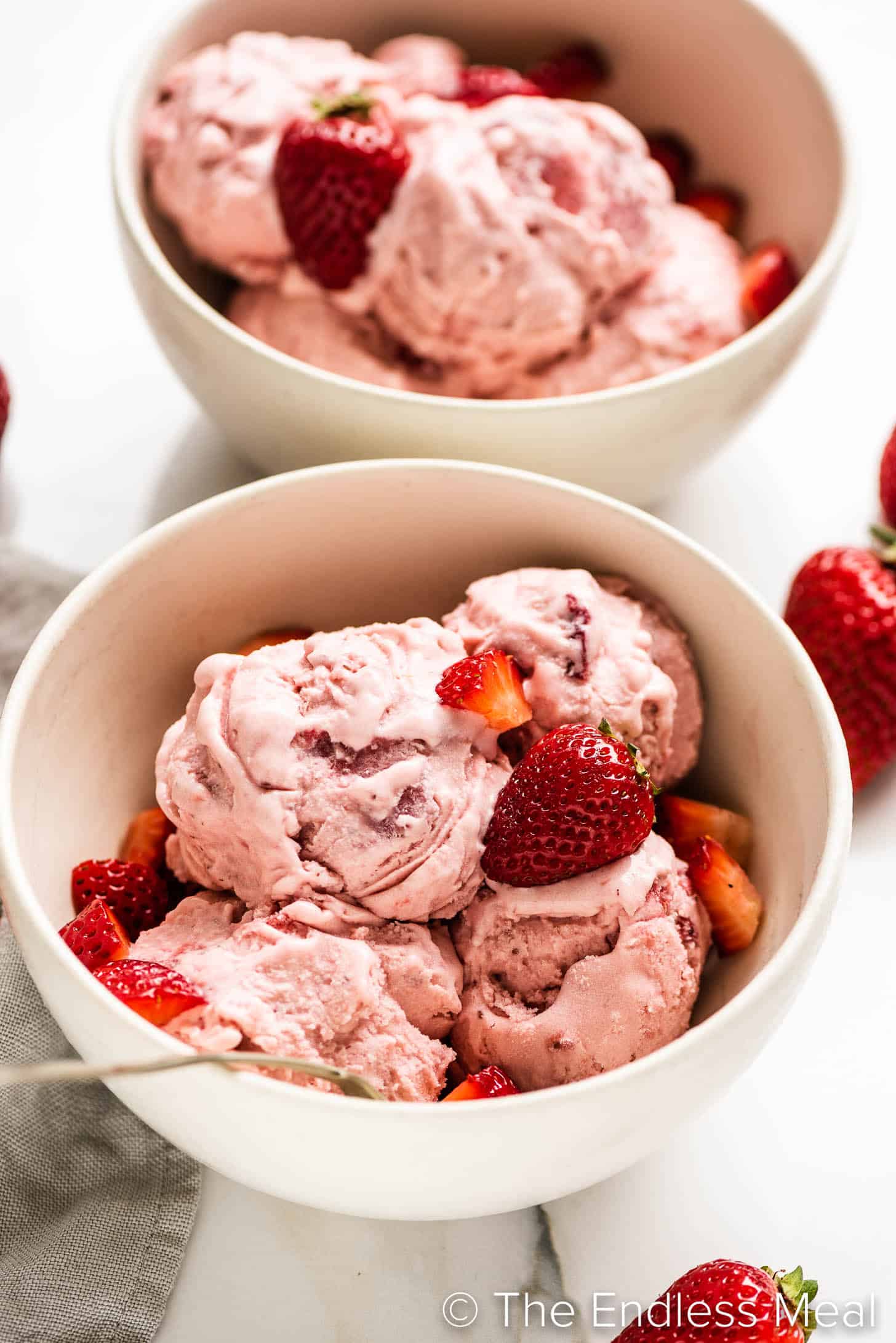 strawberry ice cream in a bowl topped with fresh strawberries