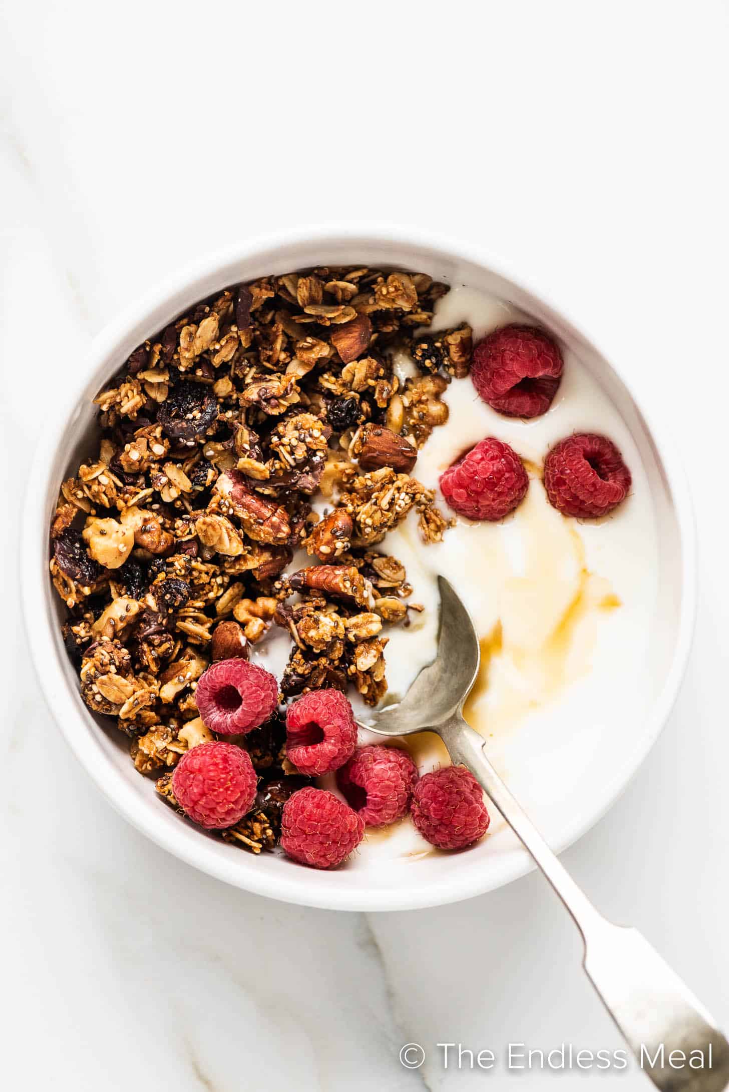 breakfast granola with superfood ingredients in a bowl with yogurt and raspberries