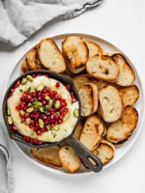 looking down on a appetizer plate with baked brie, pomegranate, and pistachios.