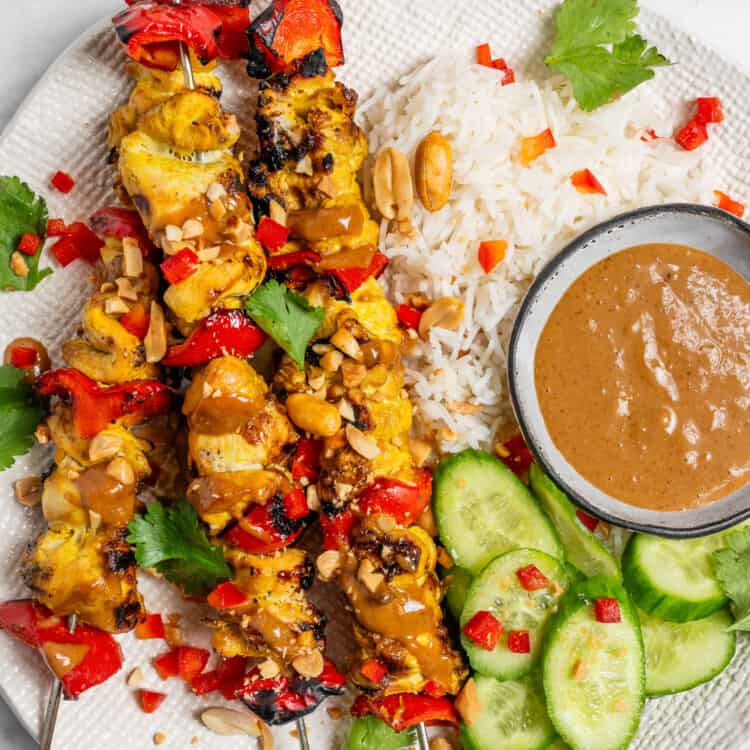 Chicken Satay Skewers on a dinner plate with rice