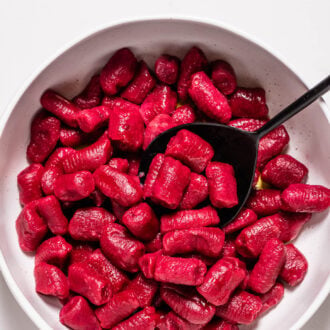 bright pink beet gnocchi in a white bowl.