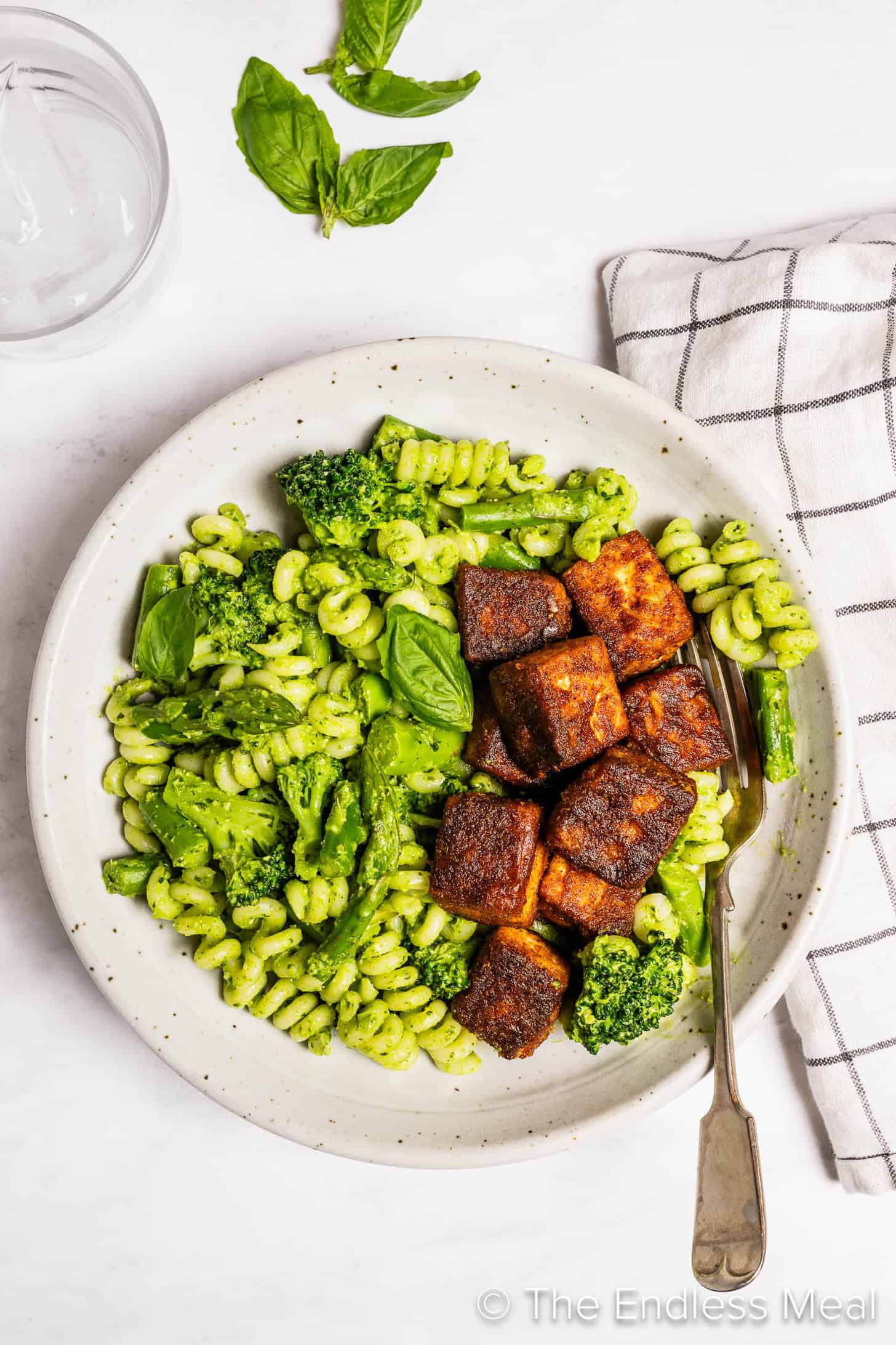 Green Pasta topped with crispy tofu on the dinner table
