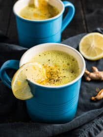 2 blue mugs filled with magic turmeric tea with lemon slices on the rim.