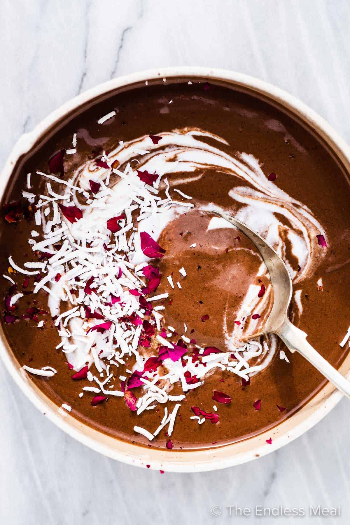 a mocha smoothie bowl with some coconut on top and a spoon inside.
