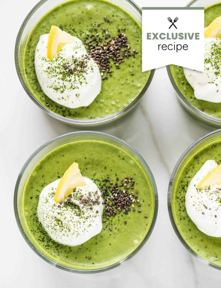 Four glass bowls filled with green smoothie, each topped with whipped cream, chia seeds, green powder, and a lemon wedge—perfect for fans of chia matcha pudding.