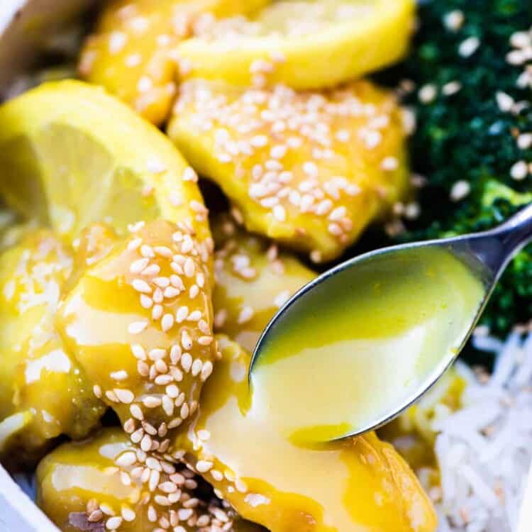 Tangy lemon sauce being poured over top of lemon chicken in a bowl.