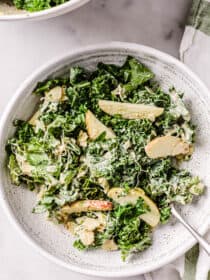 Creamy Kale tahini Salad in a white bowl with a fork.