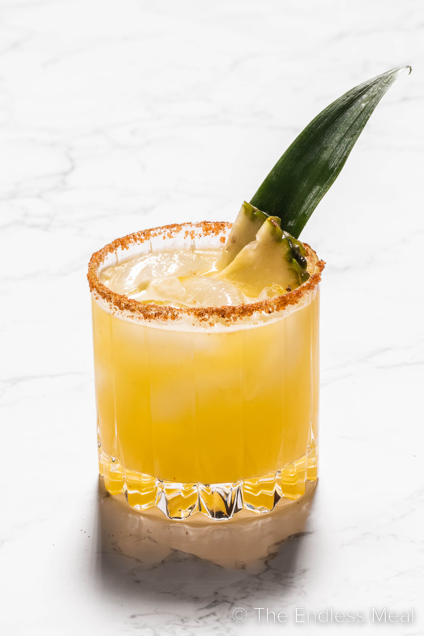 a Pineapple Margarita in a glass with spicy rim salt