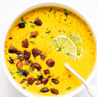 a bowl of detox sweet potato turmeric soup topped with salty almond croutons.
