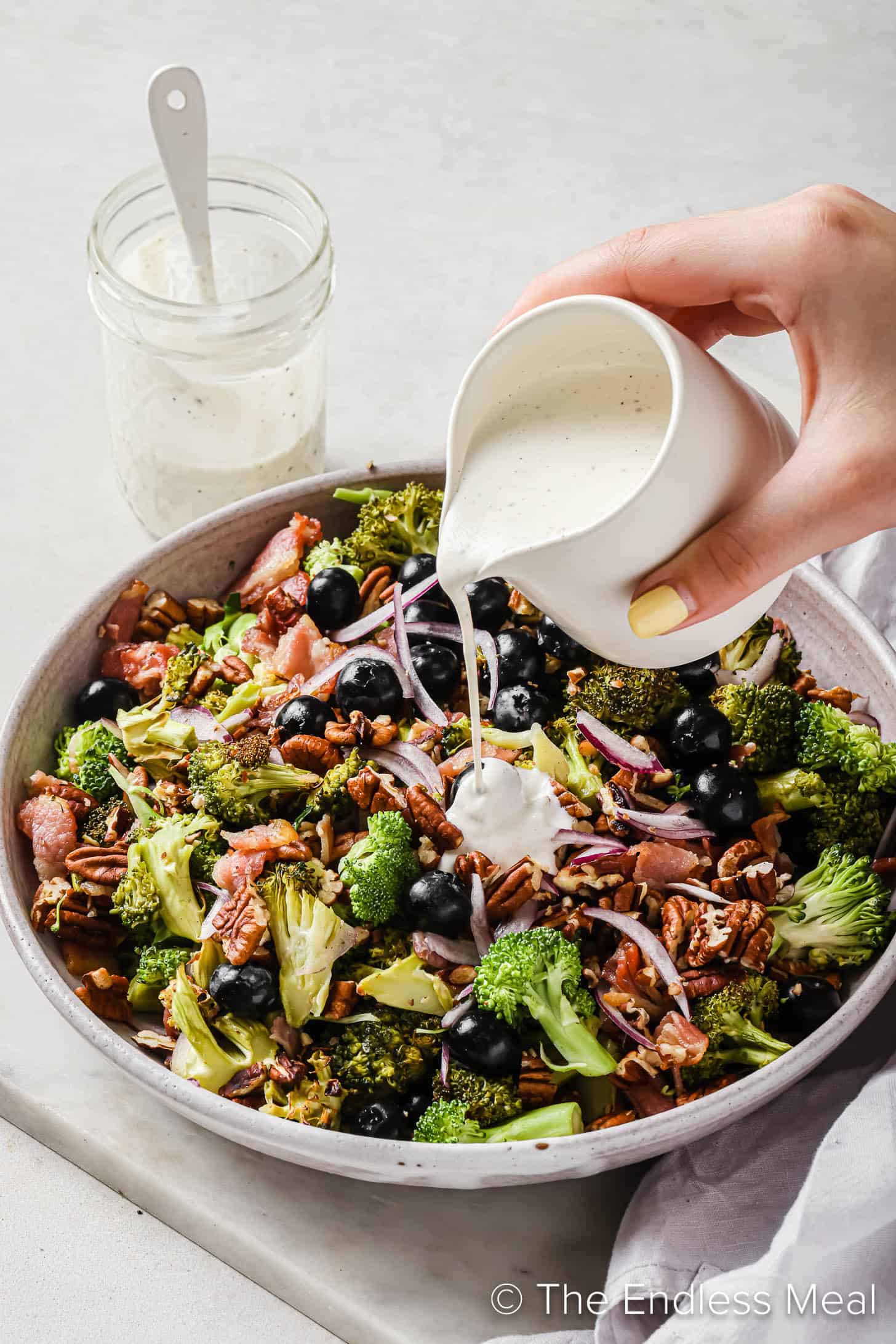 Pouring dressing over top of Blueberry Broccoli Salad
