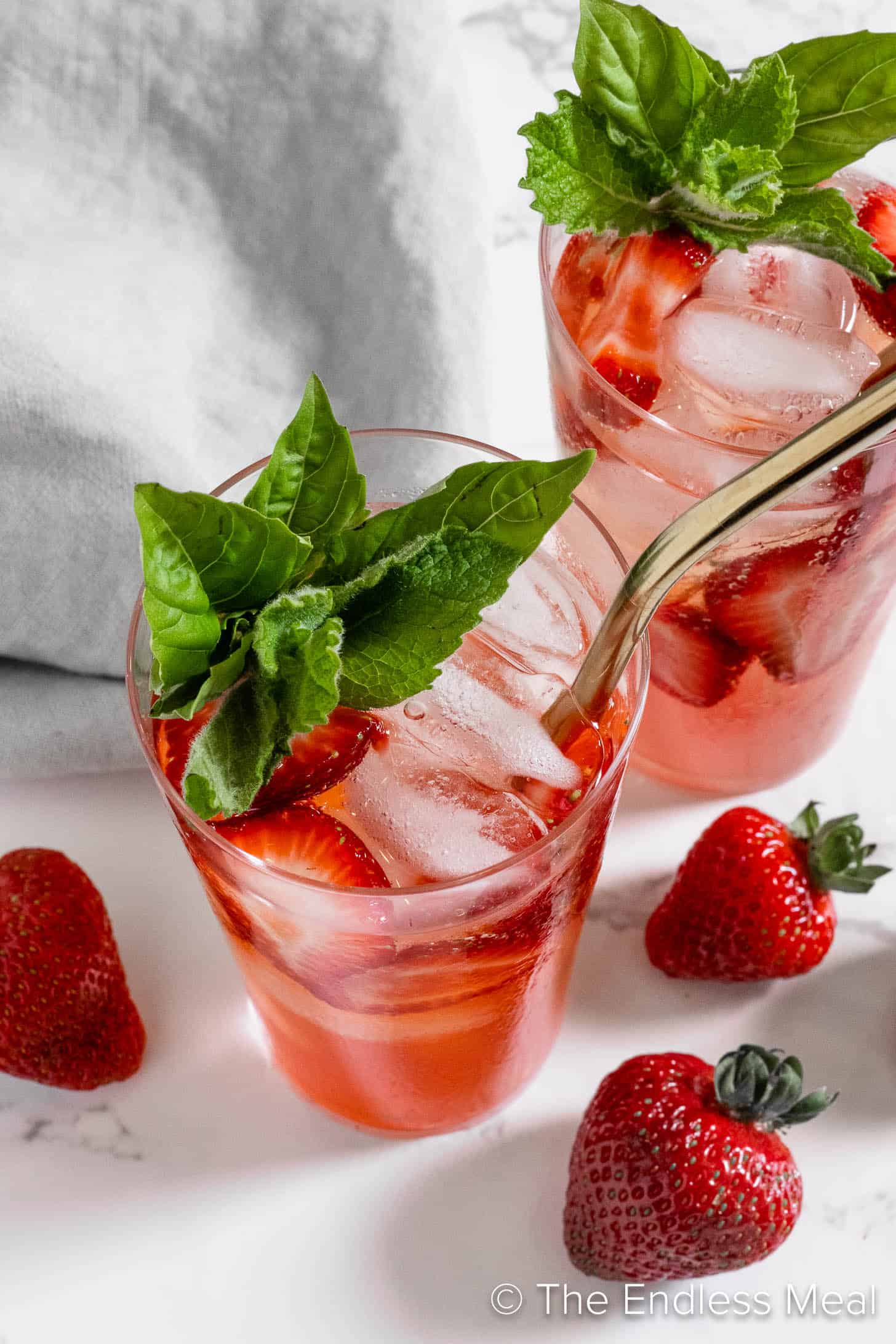 Two Strawberry Mojitos in glasses with basil and mint