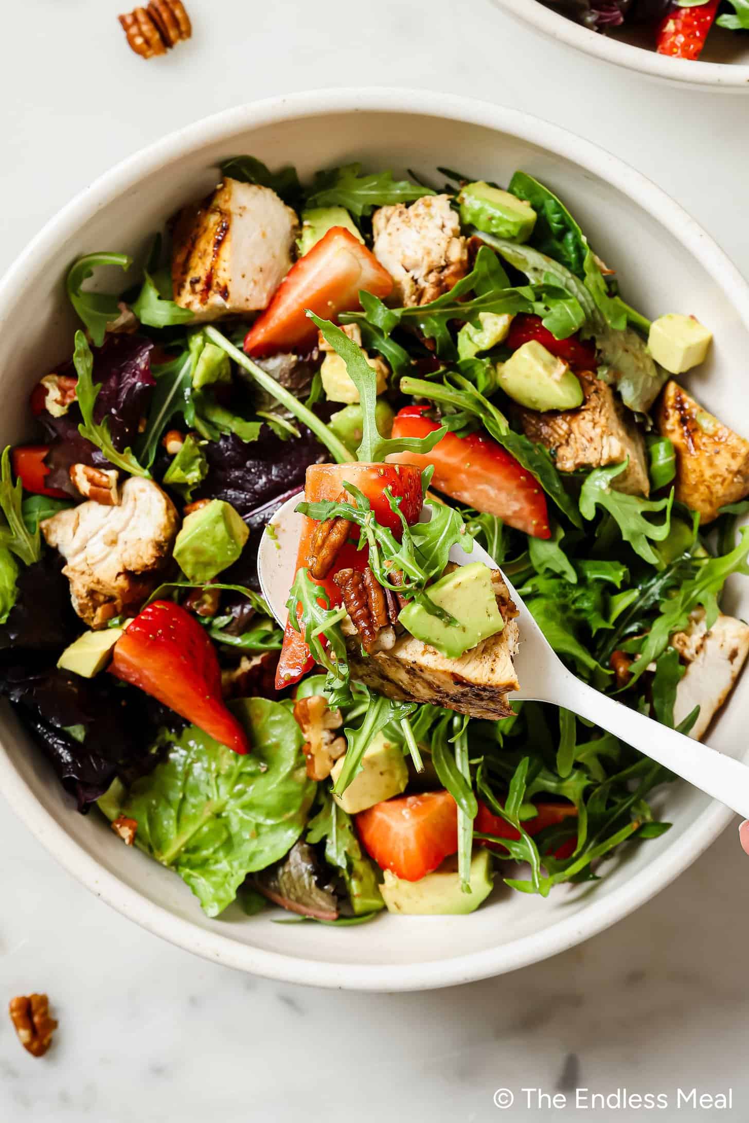 A bowl of Strawberry Balsamic Chicken Salad with a fork in it.