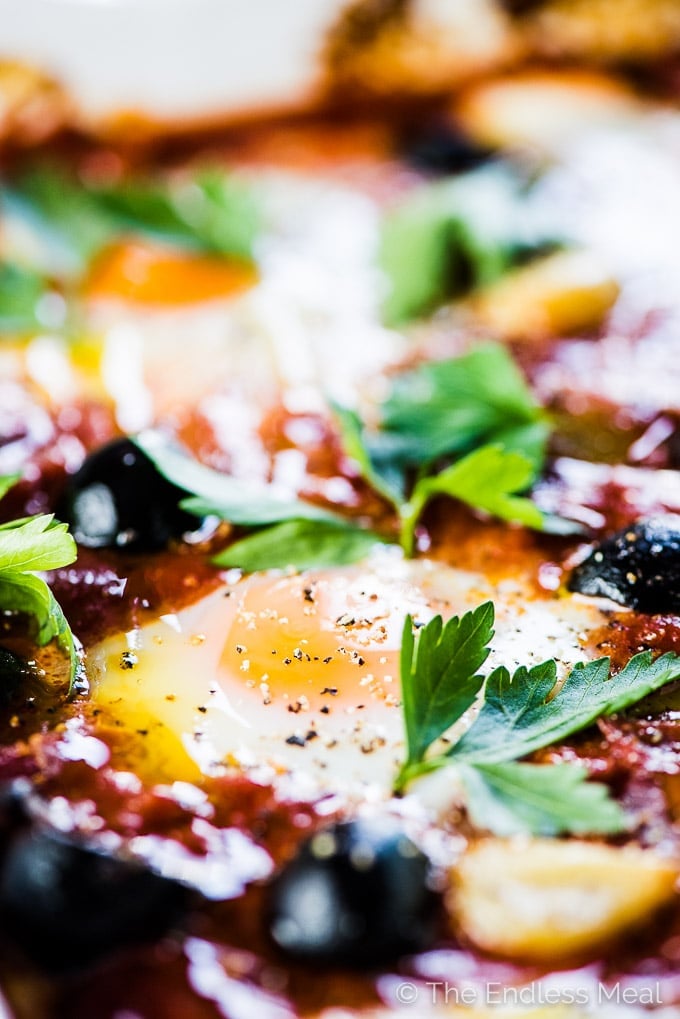Spanish Baked Eggs is made with a rich tomato sauce with whole cloves of roasted garlic and lots of plump, black Hojiblanca Olives from Spain. Eggs are baked into the sauce which is just as delicious eaten for dinner as it is for breakfast. | gluten-free + paleo + Whole30 + vegetarian option | #theendlessmeal #eggs #spanisheggs #olives #bakedeggs #breakfast #brunch