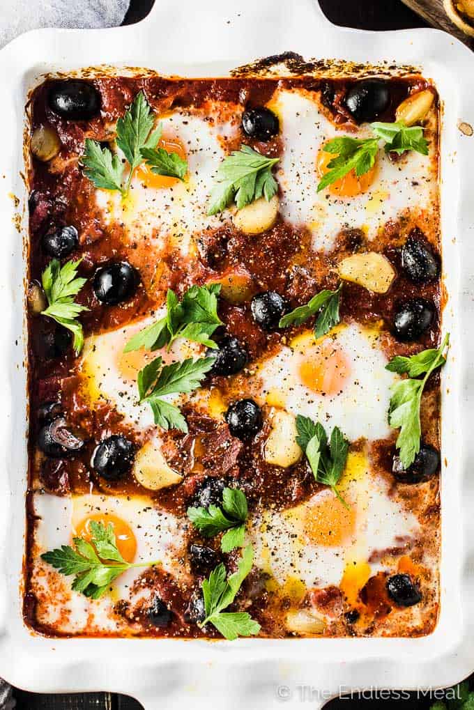 Spanish Baked Eggs is made with a rich tomato sauce with whole cloves of roasted garlic and lots of plump, black Hojiblanca Olives from Spain. Eggs are baked into the sauce which is just as delicious eaten for dinner as it is for breakfast. | paleo + Whole30 + vegetarian option | #theendlessmeal #eggs #spanisheggs #olives #bakedeggs #breakfast #brunch