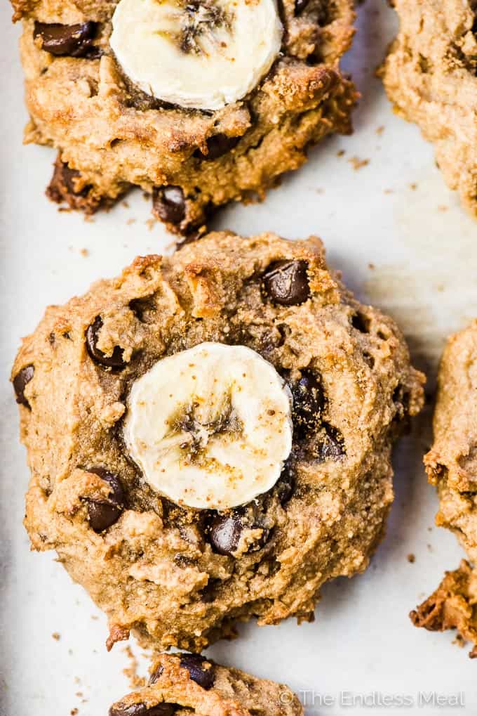 A close up of chunky monkey breakfast cookies with a banana slice pressed into the center.