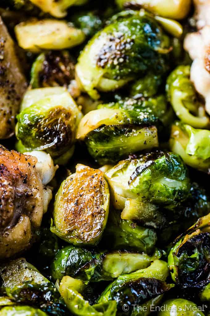 A picture of lots of browned brussels sprouts in a pan full of garlic butter chicken and brussels sprouts. 