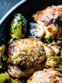 A close up of garlic butter chicken and brussels sprouts in a pan.