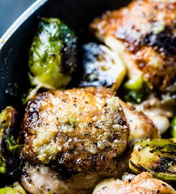 A close up of garlic butter chicken and brussels sprouts in a pan.