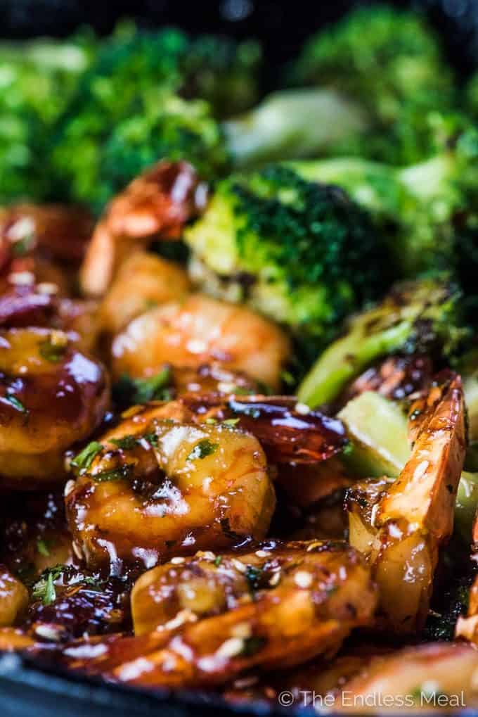 Sticky sesame honey shrimp in a pan with ginger broccoli.