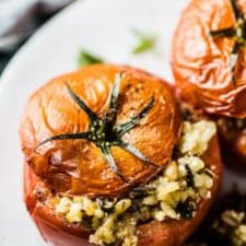 Two tomatoes stuffed with rice on a white plate.