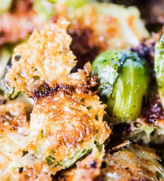 A close up shot of parmesan brussels sprouts with melted parmesan cheese sticking to the cut edge of the brussels.