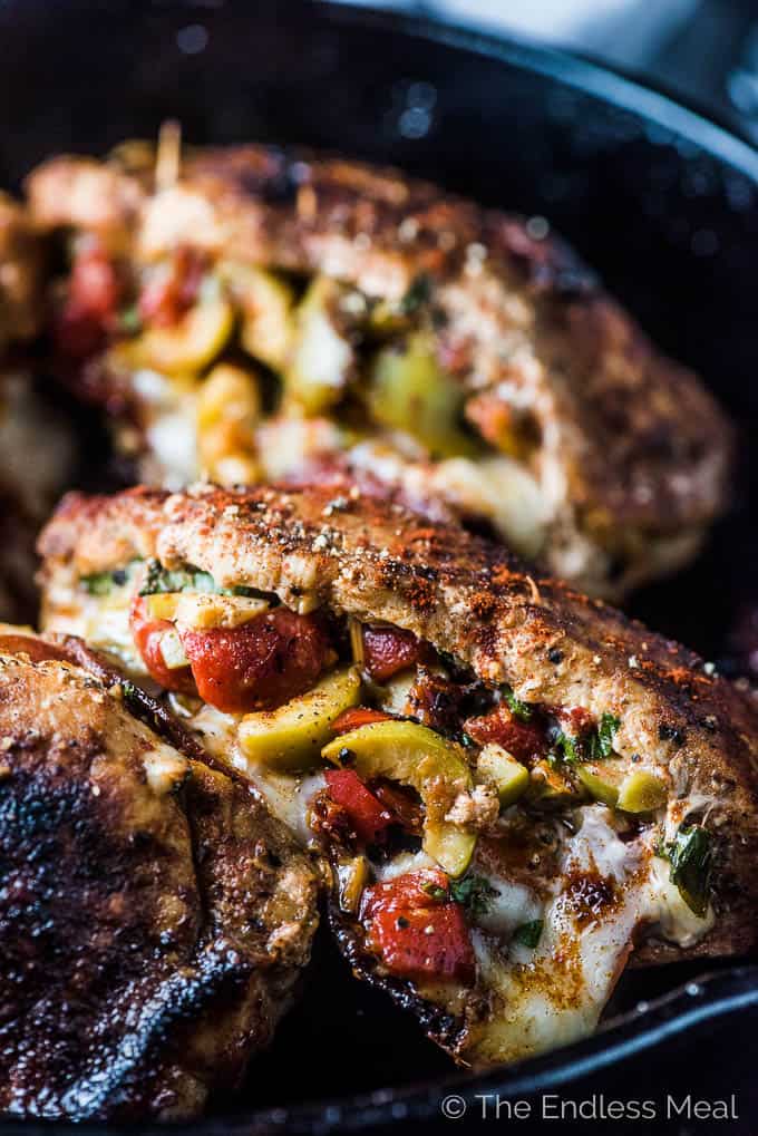 Spanish Stuffed Pork Chops in a pan with melted cheese and olives.
