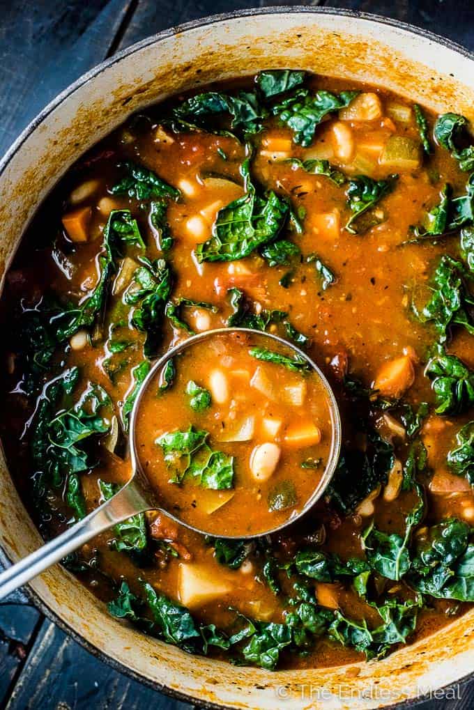 A pot of the best minestrone soup recipe with kale and a ladle in the bowl. 