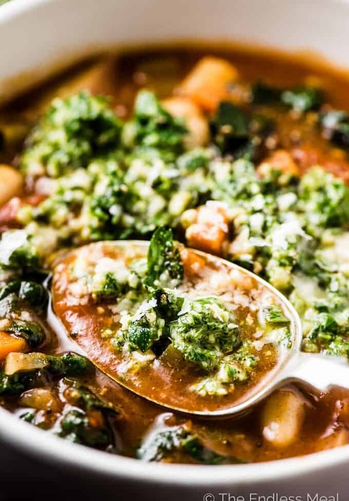 A spoonful of the best minestrone soup recipe with basil pesto on top.