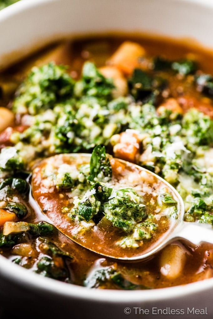 A spoonful of the best minestrone soup recipe with basil pesto on top. 