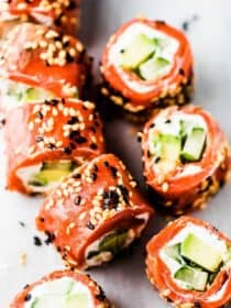 Slices of the Tzatziki Avocado Salmon Rolls on a marble tabletop.