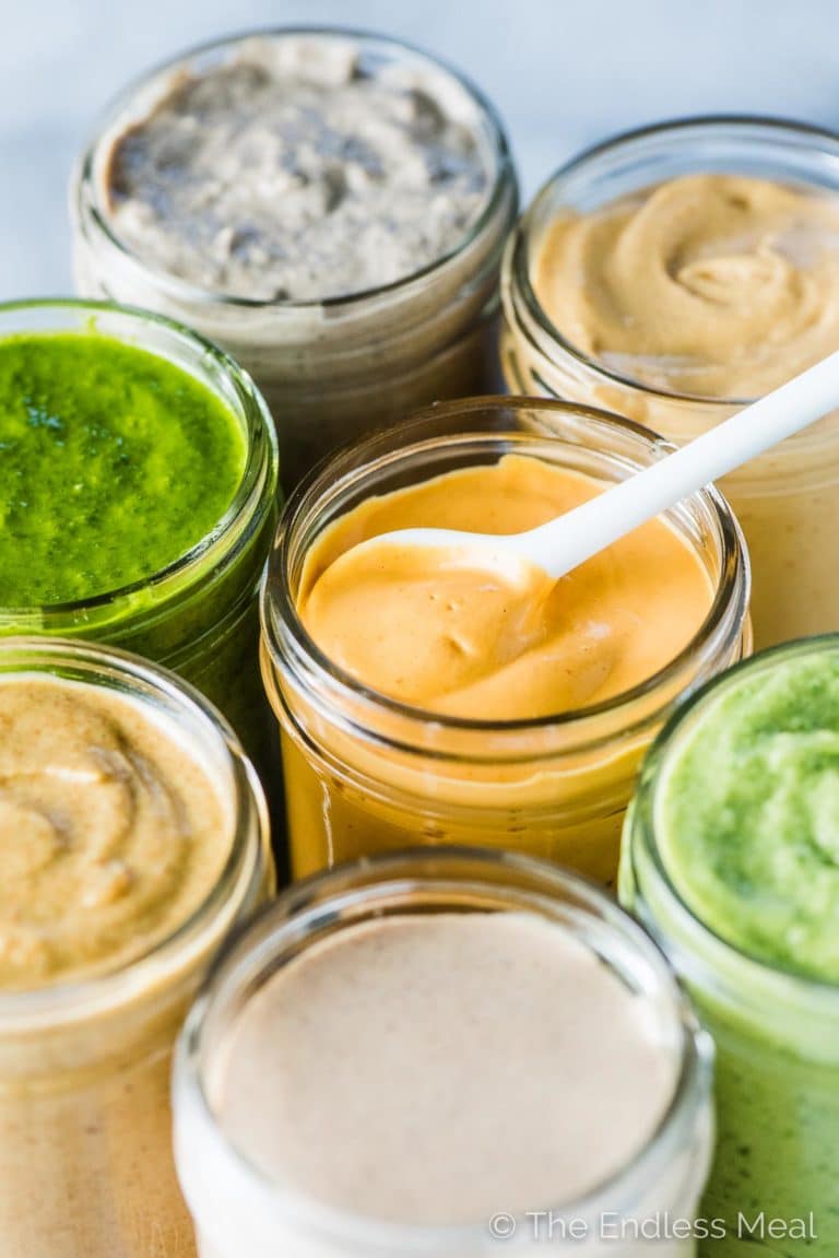 A jar of coconut curry sauce with a spoon in it and the other jars of Whole30 sauces surrounding it.