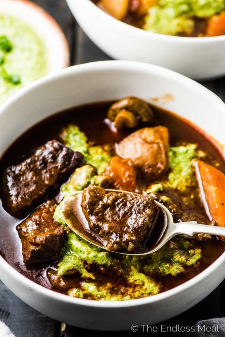 A bowl of Instant Pot Paleo Beef Stew with a spoon taking a scoop.