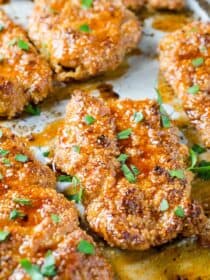 Sweet and spicy paleo chicken fingers on a baking sheet with lots of sticky glaze over top.