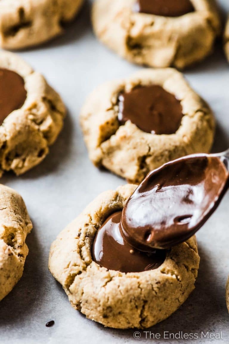 Spooning chocolate into Chocolate Almond Thumbprint Cookies.