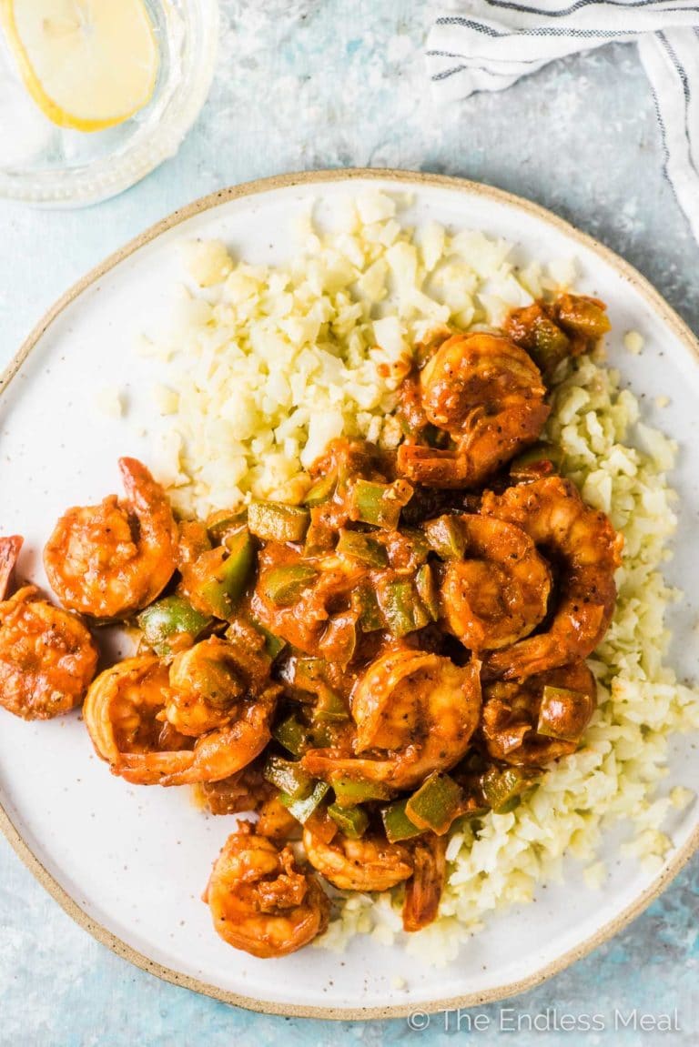 A plate of cauliflower rice topped with spicy Cajun shrimp.