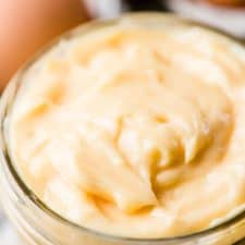 Thick homemade mayonnaise in a glass jar.