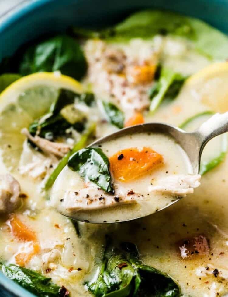 A close up shot of a spoonful of lemon chicken soup.