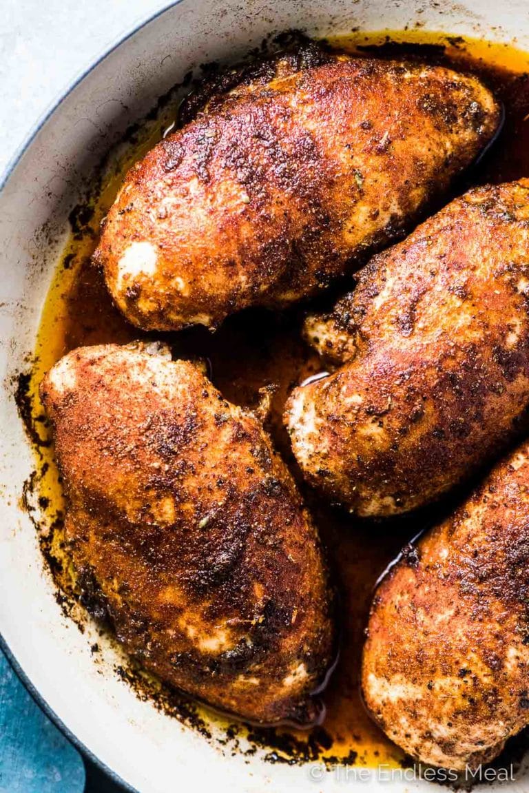A pan of juicy baked chicken breast in a baking dish. 