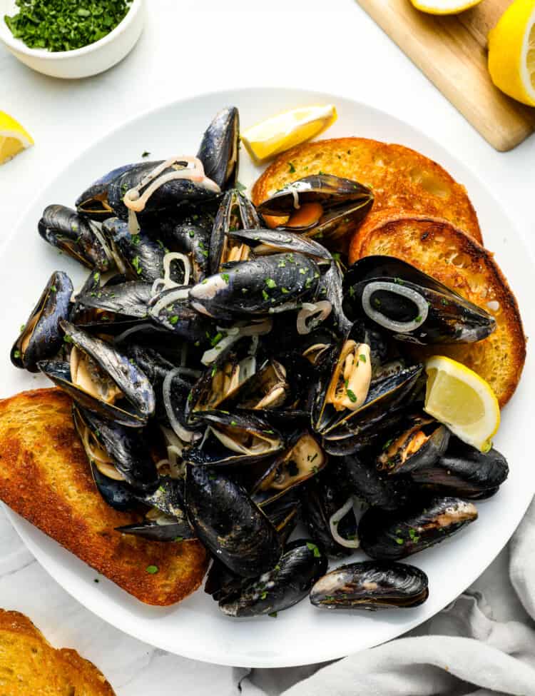 This Mussels Recipe in white wine sauce in a serving bowl with crunchy bread on the side.