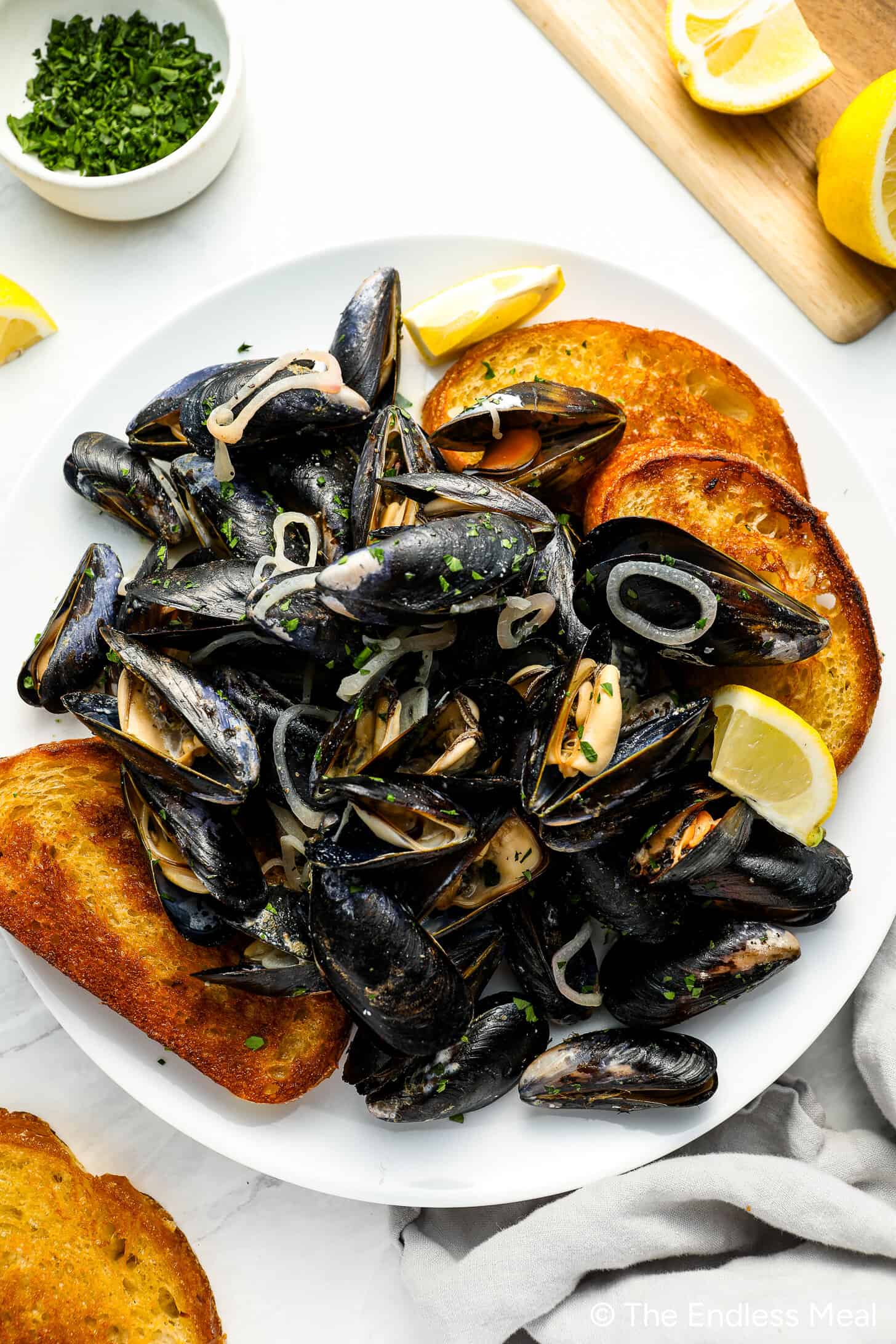 This Mussels Recipe in white wine sauce in a serving bowl with crunchy bread on the side.