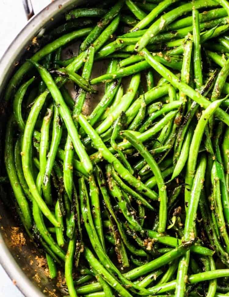 Sauteed green beans with garlic in a skillet.