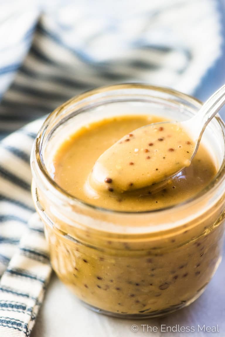 The dairy-free creamy balsamic dressing for the steak salad in a mason jar with a spoon.