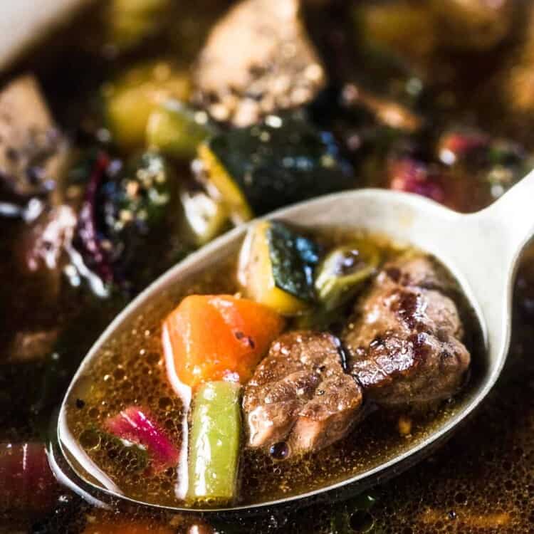 A close up of a spoonful of crockpot vegetable beef soup.