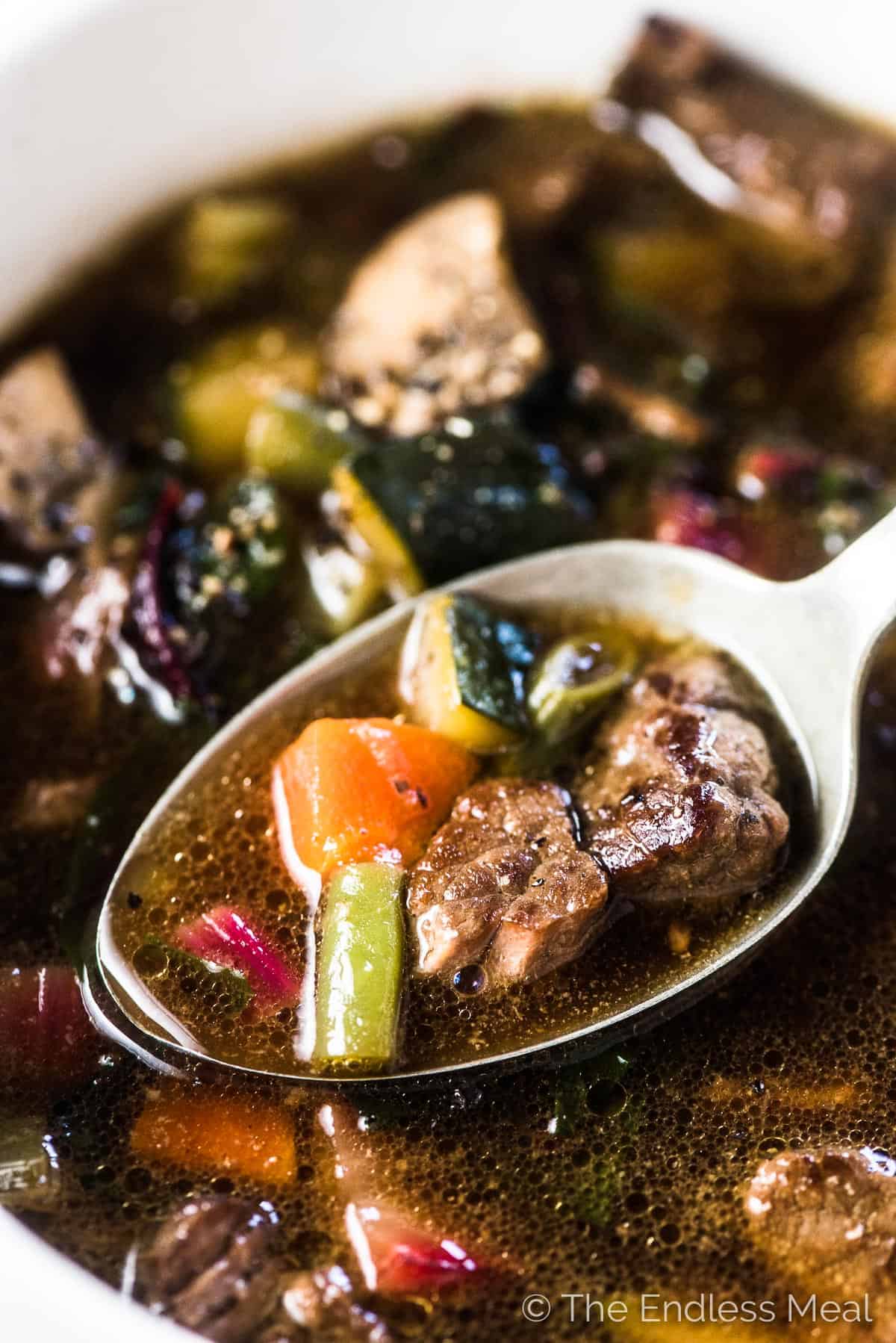 A close up of a spoonful of crockpot vegetable beef soup.