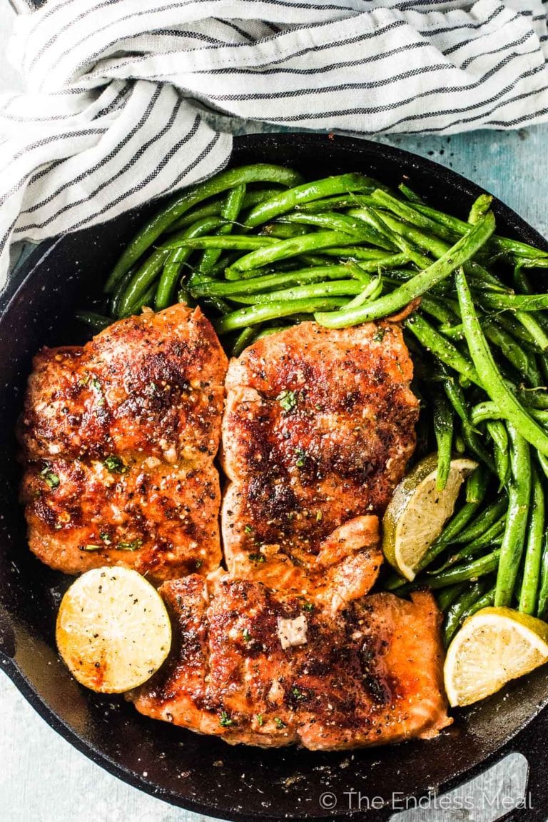 Honey salmon in a cast iron pan with green beans on the side.