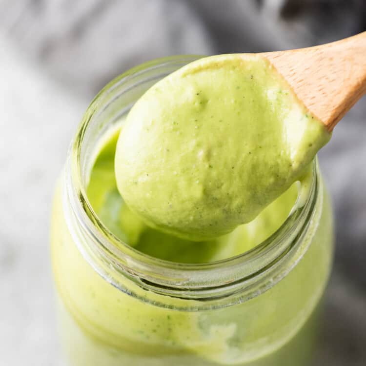 Avocado Ranch Dressing in a glass jar with a wooden spoon