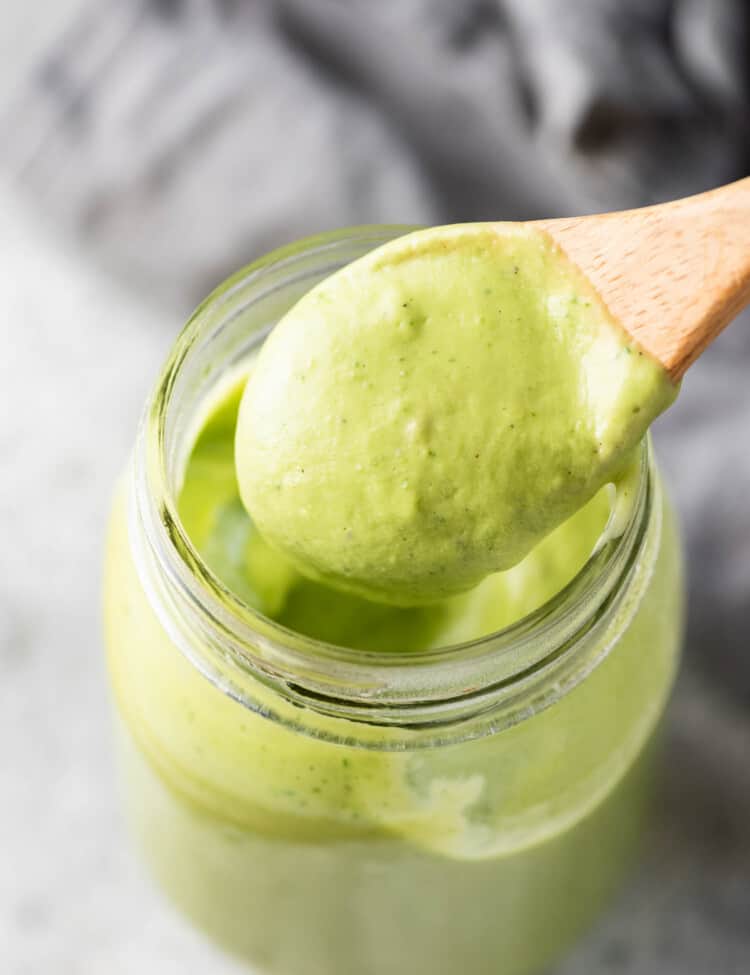Avocado Ranch Dressing in a glass jar with a wooden spoon