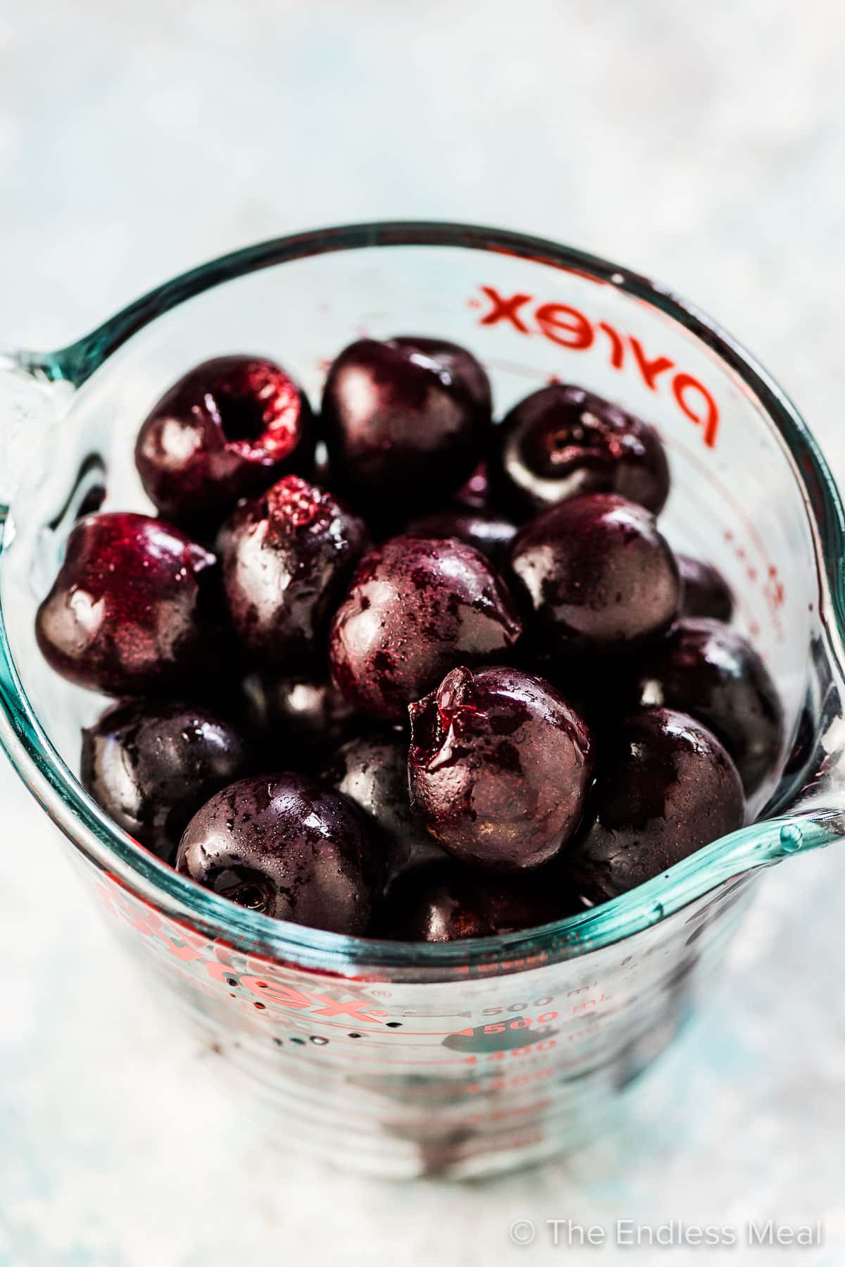 Fresh pitted cherries in a glass measuring cup ready to be made into fresh cherry sauce. 